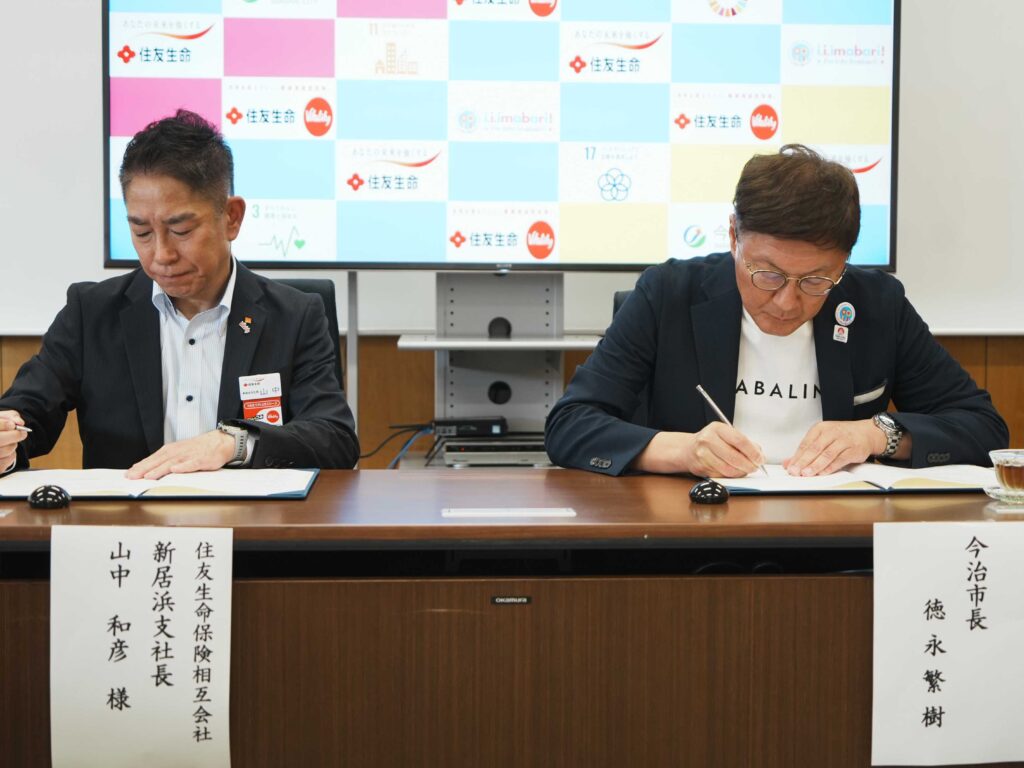 市長と新居浜支社長がサインする様子